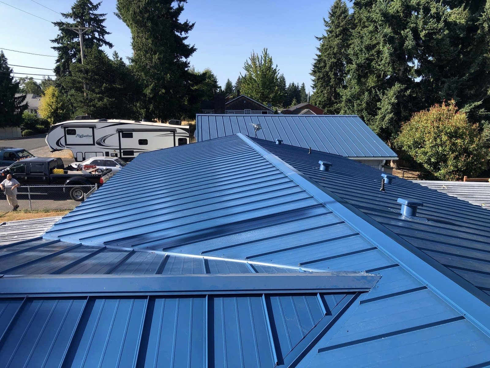Standing-seam metal roof in bold blue across connected rooflines